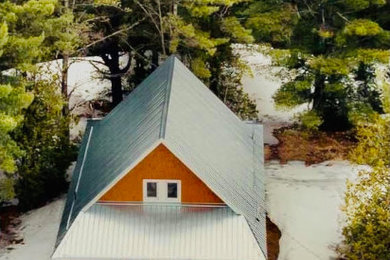 Foto de fachada de casa roja y gris campestre de tamaño medio de dos plantas con revestimiento de madera, tejado a dos aguas y tejado de metal