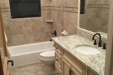 Inspiration for a mid-sized traditional bathroom in Miami with recessed-panel cabinets, beige cabinets, an alcove tub, a shower/bathtub combo, beige tile, ceramic tile, beige walls, ceramic floors, an undermount sink and granite benchtops.