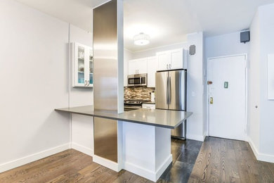 Mid-sized transitional single-wall dark wood floor and brown floor eat-in kitchen photo in Other with an undermount sink, shaker cabinets, white cabinets, stainless steel appliances and a peninsula
