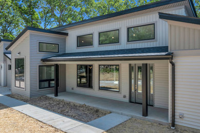 Small modern beige one-story vinyl and board and batten house exterior idea in St Louis with a butterfly roof, a shingle roof and a black roof