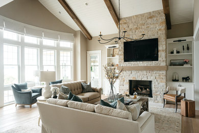 Photo of a large country enclosed family room in Detroit with beige walls, light hardwood floors, a standard fireplace, a stone fireplace surround, a built-in media wall and brown floor.