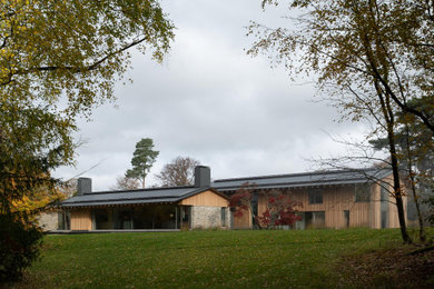 Diseño de fachada de casa multicolor y gris grande de tres plantas con revestimiento de madera, tejado a dos aguas y tejado de metal