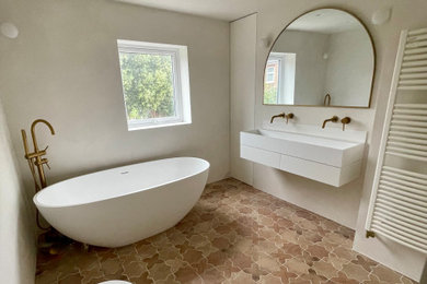 Design ideas for a large mediterranean bathroom in London with white cabinets, a freestanding bath, a wall mounted toilet, beige tiles, porcelain tiles, beige walls, porcelain flooring, a wall-mounted sink, multi-coloured floors, an open shower, feature lighting and a floating vanity unit.