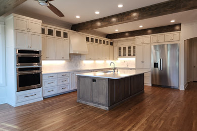 Large french country l-shaped medium tone wood floor, brown floor and coffered ceiling kitchen pantry photo in Other with an undermount sink, shaker cabinets, beige cabinets, quartz countertops, white backsplash, ceramic backsplash, stainless steel appliances, an island and white countertops