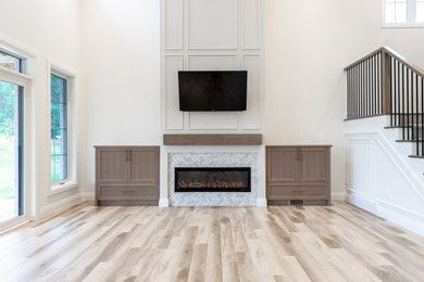 Example of a mid-sized transitional open concept laminate floor, brown floor and wall paneling living room design in Toronto with white walls, a standard fireplace, a tile fireplace and a wall-mounted tv