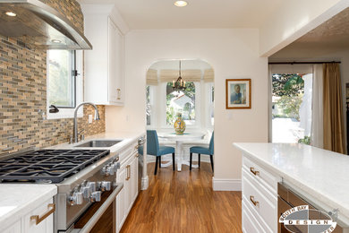 Inspiration for a mid-sized transitional light wood floor and brown floor kitchen remodel in Los Angeles with an undermount sink, raised-panel cabinets, white cabinets, quartz countertops, brown backsplash, porcelain backsplash, stainless steel appliances and no island