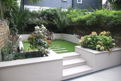 This is an example of a small contemporary back partial sun garden wall in London with a retaining wall.
