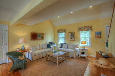 Expansive beach style open concept living room in Boston with yellow walls and medium hardwood floors.
