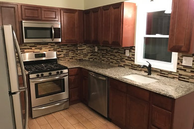 Example of a small classic u-shaped ceramic tile kitchen design in Philadelphia with an undermount sink, raised-panel cabinets, medium tone wood cabinets, granite countertops, beige backsplash, glass tile backsplash and stainless steel appliances