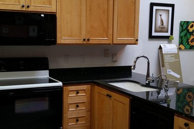 Open concept kitchen - mid-sized transitional l-shaped ceramic tile open concept kitchen idea in Richmond with an undermount sink, recessed-panel cabinets, light wood cabinets, quartzite countertops, black backsplash, stone slab backsplash, black appliances and an island