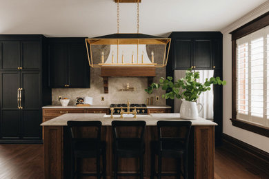 Elegant kitchen photo in Montreal with dark wood cabinets, marble countertops, marble backsplash and black appliances