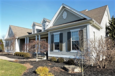 Large elegant beige two-story concrete fiberboard gable roof photo in Other with a shingle roof
