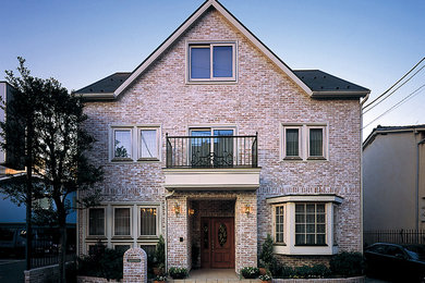 This is an example of a traditional three-storey brick pink house exterior in Other with a gable roof.