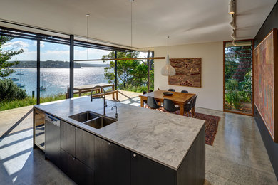 Photo of a mid-sized modern galley eat-in kitchen in Sydney with a double-bowl sink, flat-panel cabinets, light wood cabinets, quartz benchtops, white appliances, concrete floors, with island and multi-coloured benchtop.