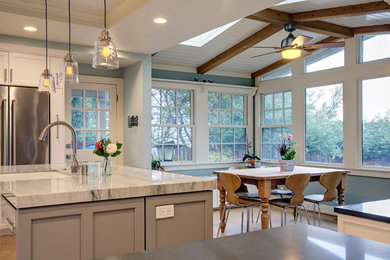 Inspiration for a mid-sized transitional u-shaped light wood floor and yellow floor eat-in kitchen remodel in San Francisco with a farmhouse sink, shaker cabinets, white cabinets, quartzite countertops, green backsplash, subway tile backsplash, stainless steel appliances and an island