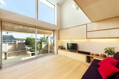 Modern living room in Other with beige walls, light hardwood floors, a freestanding tv and beige floor.