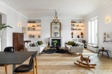 This is an example of a large contemporary living room in Paris with white walls, light hardwood floors, a standard fireplace and beige floor.