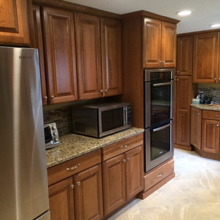 Design ideas for a mid-sized arts and crafts u-shaped kitchen pantry in Boston with raised-panel cabinets, medium wood cabinets, granite benchtops, brown splashback, stainless steel appliances, terrazzo floors and a peninsula.