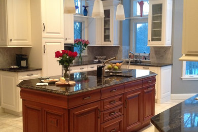 Example of a mid-sized transitional u-shaped travertine floor and beige floor eat-in kitchen design in New York with an undermount sink, raised-panel cabinets, white cabinets, granite countertops, beige backsplash, stone tile backsplash, stainless steel appliances and an island