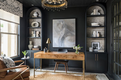 Modelo de despacho moderno de tamaño medio sin chimenea con biblioteca, paredes negras, suelo de madera oscura, escritorio empotrado, suelo marrón, madera y papel pintado