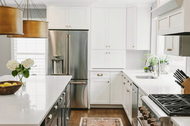 Example of a transitional medium tone wood floor and brown floor kitchen design in DC Metro with a single-bowl sink, shaker cabinets, white cabinets, quartz countertops, white backsplash, ceramic backsplash, white appliances, an island and white countertops