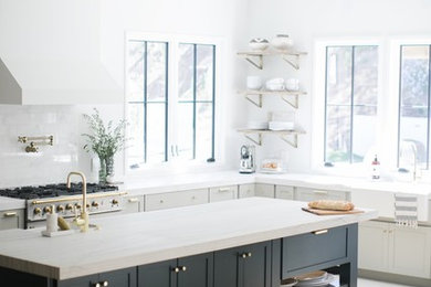 Large trendy l-shaped light wood floor and brown floor open concept kitchen photo in Orange County with a farmhouse sink, shaker cabinets, blue cabinets, marble countertops, white backsplash, marble backsplash, paneled appliances, an island and white countertops