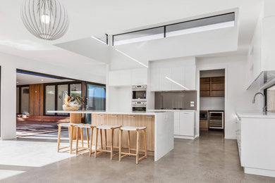 Design ideas for a mid-sized contemporary u-shaped eat-in kitchen in Melbourne with a drop-in sink, flat-panel cabinets, brown cabinets, quartz benchtops, white splashback, glass sheet splashback, stainless steel appliances, ceramic floors, with island, beige floor and white benchtop.
