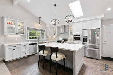 Example of a classic l-shaped porcelain tile and multicolored floor eat-in kitchen design in San Francisco with an undermount sink, raised-panel cabinets, white cabinets, quartz countertops, gray backsplash, porcelain backsplash, stainless steel appliances, an island and white countertops