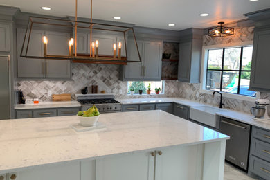 Eat-in kitchen - large transitional u-shaped marble floor and gray floor eat-in kitchen idea in Oklahoma City with a farmhouse sink, recessed-panel cabinets, blue cabinets, quartz countertops, white backsplash, marble backsplash, stainless steel appliances, an island and white countertops