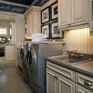 Design ideas for a medium sized traditional single-wall separated utility room in Denver with a built-in sink, a side by side washer and dryer, grey floors, raised-panel cabinets, distressed cabinets, concrete worktops, ceramic flooring and black walls.