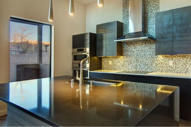 Mid-sized minimalist single-wall dark wood floor and brown floor open concept kitchen photo in Albuquerque with an undermount sink, flat-panel cabinets, dark wood cabinets, quartz countertops, multicolored backsplash, glass tile backsplash, stainless steel appliances, an island and white countertops
