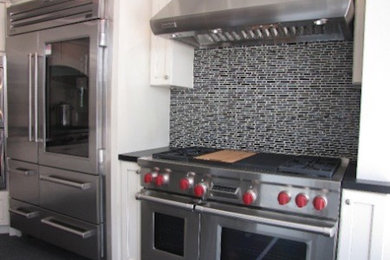 Example of a kitchen design in Other with granite countertops, gray backsplash, glass tile backsplash and stainless steel appliances