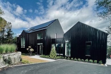 Inspiration for a mid-sized modern black two-story metal house exterior remodel in Toronto with a metal roof and a black roof