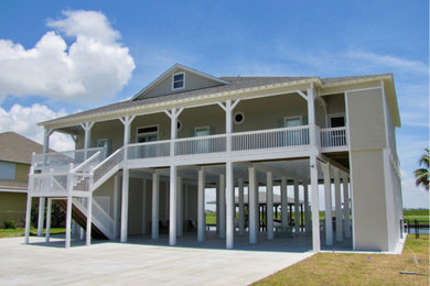 Photo of a large beach style two-storey grey house exterior in Houston with wood siding, a hip roof and a shingle roof.