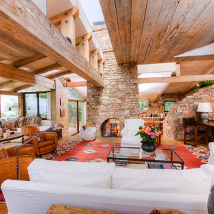 Diseño de salón abierto, mediterráneo, extra grande, con paredes beige, suelo de madera clara, chimenea de doble cara y marco de chimenea de piedra