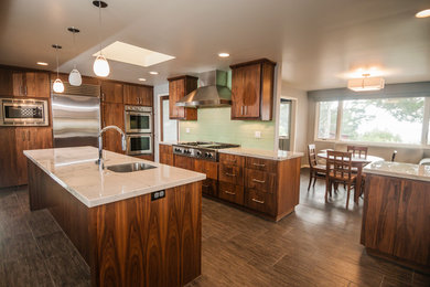 This is an example of a large modern u-shaped open plan kitchen in San Francisco with a double-bowl sink, flat-panel cabinets, dark wood cabinets, quartzite benchtops, green splashback, glass tile splashback, stainless steel appliances, porcelain floors and with island.