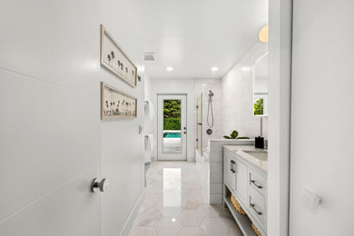 Mid-sized trendy white tile and marble tile marble floor, white floor and single-sink alcove bathtub photo in Miami with shaker cabinets, white cabinets, a one-piece toilet, white walls, an undermount sink, marble countertops, beige countertops and a freestanding vanity