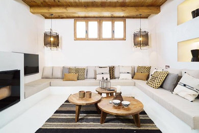 Modelo de salón abierto mediterráneo de tamaño medio con paredes blancas, suelo de cemento, todas las chimeneas, marco de chimenea de hormigón, televisor colgado en la pared y suelo blanco