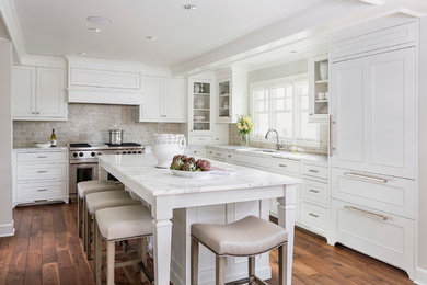 Photo of a mid-sized traditional l-shaped kitchen in Minneapolis with recessed-panel cabinets, subway tile splashback, panelled appliances, white cabinets, marble benchtops, grey splashback, an undermount sink, dark hardwood floors, with island and white benchtop.