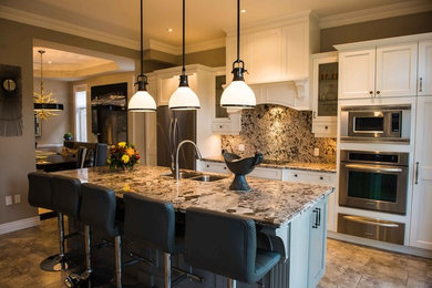 This is an example of a mid-sized transitional single-wall eat-in kitchen in Toronto with an undermount sink, recessed-panel cabinets, white cabinets, granite benchtops, multi-coloured splashback, stone slab splashback, stainless steel appliances, with island, beige floor and multi-coloured benchtop.