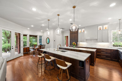 Kitchen - galley medium tone wood floor and brown floor kitchen idea in Dallas with an undermount sink, flat-panel cabinets, dark wood cabinets, quartzite countertops, white backsplash, marble backsplash, stainless steel appliances, two islands and white countertops