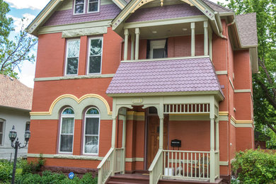 This is an example of a mid-sized victorian front porch design in Denver with a roof extension.