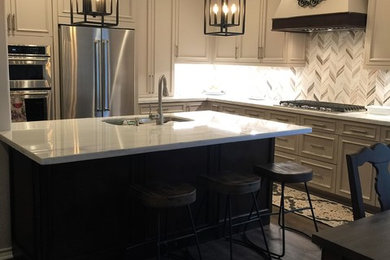 Example of a mid-sized transitional l-shaped vinyl floor and brown floor enclosed kitchen design in Houston with a double-bowl sink, flat-panel cabinets, beige cabinets, wood countertops, beige backsplash, marble backsplash, stainless steel appliances and an island