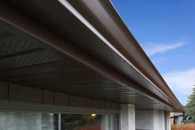 Mid-sized gray one-story stucco gable roof photo in Calgary