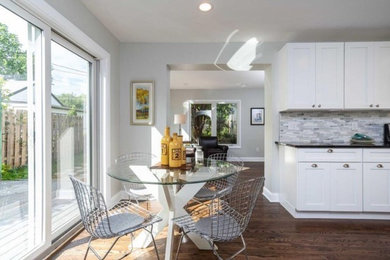 Inspiration for a transitional medium tone wood floor kitchen remodel in Minneapolis with raised-panel cabinets, white cabinets, stone tile backsplash, a peninsula and black countertops