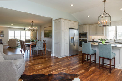 Open concept kitchen - large transitional u-shaped medium tone wood floor and brown floor open concept kitchen idea in Kansas City with a single-bowl sink, recessed-panel cabinets, gray cabinets, granite countertops, white backsplash, marble backsplash, stainless steel appliances and an island