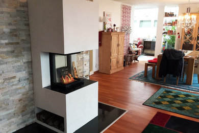 Großes, Offenes Rustikales Wohnzimmer mit weißer Wandfarbe, dunklem Holzboden, Kamin, verputzter Kaminumrandung, TV-Wand und rotem Boden in Nürnberg