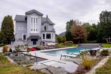 Aménagement d'un piscine avec aménagement paysager arrière classique de taille moyenne et rectangle avec des pavés en pierre naturelle.