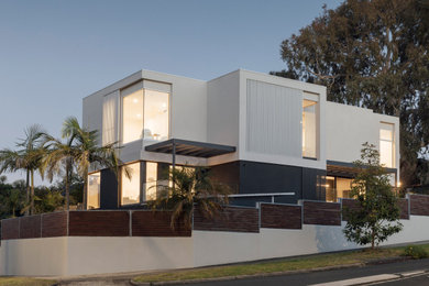 This is an example of a mid-sized contemporary three-storey stucco white house exterior in Melbourne with a flat roof.