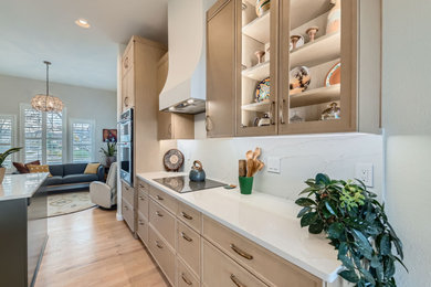 Inspiration for a contemporary medium tone wood floor and brown floor eat-in kitchen remodel in Denver with an undermount sink, glass-front cabinets, light wood cabinets, granite countertops, white backsplash, stone slab backsplash, stainless steel appliances, an island and white countertops